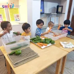 A group of young children gathers around the table to wash and prepare vegetables. Working together on a shared goal teaches them cooperation and social skills.