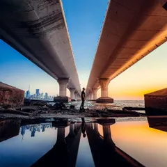 A unique perspective of the Bandra-Worli Sea Link in Mumbai. I used a puddle to create a perfect reflection, framing myself against the iconic bridge and the city skyline at sunset.