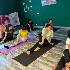 Celebrating International Yoga Day with a focused session. An instructor provides a hands-on adjustment to a student in a seated spinal twist. This ensures correct alignment and helps deepen the stretch safely.