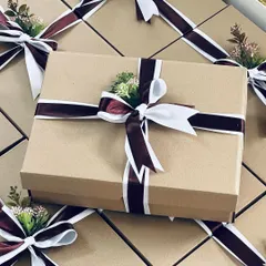 A large order of corporate gifts, elegantly packed in simple cardboard boxes with a beautiful two-toned ribbon and a touch of floral decor.