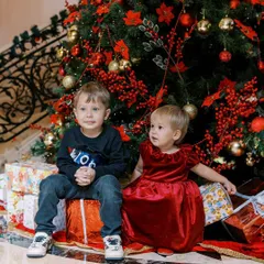 A brother and sister sitting together by the Christmas tree. A quiet moment of togetherness during the magical holiday season.