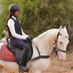 A female rider looking focused and confident on a trail ride. Our safaris are for everyone who is ready for an adventure.