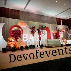 A wider perspective of the "Baby Puji" baby shower. This view shows the full stage composition, including the large moon prop, creating a dreamy and celebratory setting.