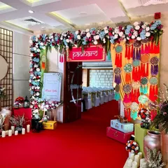 A colorful and festive entrance featuring a 'Padharo' sign, multi-colored dreamcatchers, and a lush floral arch, setting the stage for a vibrant event.