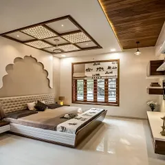 An elegant bedroom with an ornate false ceiling and a traditional arch detail behind the bed, blending classic and modern elements.