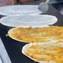 A chef expertly preparing fresh dosas on a large griddle at one of our outdoor events. Live cooking adds a special touch to any celebration.