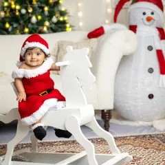 A tiny Santa's helper on a classic white rocking horse. This adorable shot captures the pure innocence and magic of a baby's first Christmas.