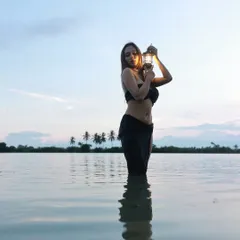 An artistic and sensuous concept shoot at a lakeside. The combination of the water, the fading light, and the single lantern creates a powerful, moody visual that stands out.