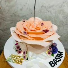 A stunning cake sculpted into a blooming peach-colored rose, with a single candle in the center.