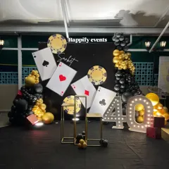 A high-stakes Casino Night theme for a 40th birthday. The backdrop features oversized playing cards, casino chips, and a light-up marquee number.