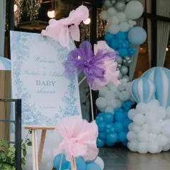 The welcome sign for a blue-themed baby shower, adorned with large, artistic paper flowers and set against a backdrop of a blue, white, and silver balloon arch.