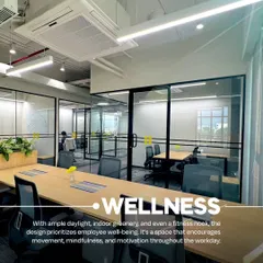 An open-plan desk area at VentureX designed with wellness in mind. The space features ample daylight, integrated greenery in the desk dividers, and ergonomic seating to promote employee well-being throughout the workday.