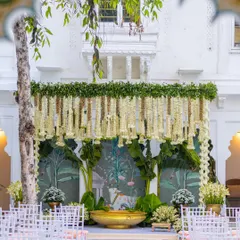 I love creating timeless looks, like this South Indian ceremony setup. The stage features a canopy of hanging jasmine and tuberose, traditional banana plantains, and a beautiful hand-painted backdrop, all coming together for an authentic and elegant wedding atmosphere.