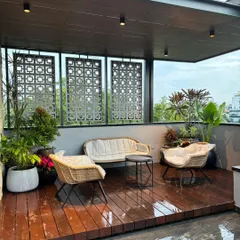 A complete terrace transformation designed for relaxation and entertaining. This space features a raised wooden deck, comfortable all-weather seating, decorative privacy screens, and a variety of tropical plants to create a private urban oasis.