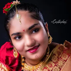 A close-up portrait capturing the warmth and beauty of a traditional look. This shot focuses on the intricate details of the jewelry, makeup, and the happy expression of the subject.