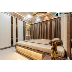 This bedroom in Bhiwandi features a unique bed with an illuminated base and a backdrop of textured wallpaper and cove lighting. The sliding wardrobe with mirrored strips enhances the sense of space and adds a modern touch.