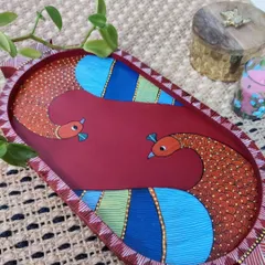 An elegant oval tray hand-painted with a colorful peacock design. The intricate patterns and vibrant colors make this a standout piece for your coffee table or for serving special treats.
