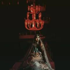 A moody and dramatic bridal portrait, with the bride seated under a grand chandelier, creating a very cinematic feel.