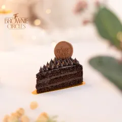 A slice of my Chocolate Ganache pastry. You can see the rich layers of chocolate cake and creamy ganache, topped with our signature chocolate logo.