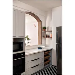 In this minimalist kitchen, we focused on clean lines and a calm, neutral palette. An arched pass-through window, lined with wood, opens up the space and connects it to the living area. The design is simple but thoughtful, with integrated appliances and open shelving for a look that is both highly functional and effortlessly chic.