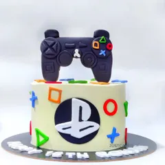A sleek PlayStation theme cake for a gaming enthusiast's 18th birthday. It features a handmade, edible controller and the iconic button symbols for a clean and modern design.
