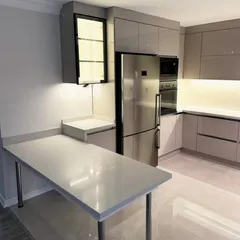This kitchen includes a versatile table-style island with a white quartz top and chrome legs. It provides extra prep space and can be used as a dining table, making it a flexible addition to the kitchen.