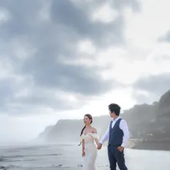 A candid moment of laughter on a beautiful Bali beach. The overcast sky creates a soft, even light that is perfect for capturing natural emotions and the stunning coastal scenery.