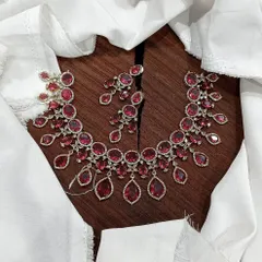 A stunning ruby-red necklace set with a contemporary design. The flat lay on a wooden surface highlights the rich color and brilliant sparkle of the stones.