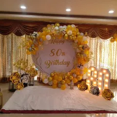 I also specialize in elegant decorations for milestone birthdays, like this 80th birthday celebration. The design features a classy gold and white color scheme, a large custom backdrop, marquee light-up numbers, and beautiful paper flowers for a sophisticated look.