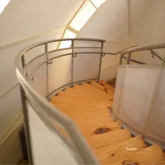 The curved wooden staircase inside the kindergarten's shell structure. The design is playful and safe, with translucent panels that maintain a sense of openness and light.