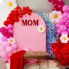 A fun and vibrant photo booth setup for Mother's Day. This design includes a pink arch, a sequin panel, and a bold balloon arrangement with cute daisy accents.