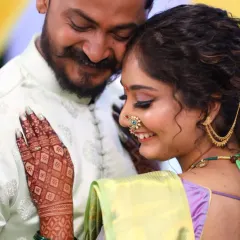 A candid moment from an engagement ceremony, where the rich color of the bride's henna shines. The design features a classic jaal (net) pattern on the back of the hand.
