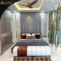 A master bedroom that defines modern luxury with its striking grey and gold theme. The design includes a floor-to-ceiling upholstered headboard with gold inlay, a custom two-tone bench, and elegant metallic room dividers for a touch of glamour.