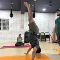 Mastering a block-supported headstand (Sirsasana) requires immense core strength and control, as shown by this student.