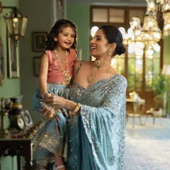 A heartwarming mother-daughter moment from the Tanishq 'Dharohar' campaign. The styling uses complementary pastel outfits and coordinated gold jewellery to visually represent the bond and shared heritage between generations.