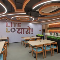 This cafeteria's motto is "Lite Lo Yaaro!" (Take it easy, friends!). The space features playful typography, creative ceiling details, and comfortable seating to encourage employees to relax and socialize.