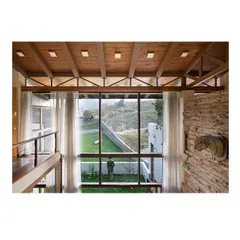 A view from the upper-level bridge, looking down into the double-height living room and out to the backyard. This perspective shows the vertical volume of the space and the extensive use of glass to maintain a constant connection with the landscape.