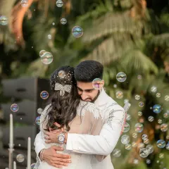 Surrounded by a magical cloud of bubbles, the couple shares a tender hug. This whimsical and romantic moment perfectly captures the fairytale feeling of their white wedding day.