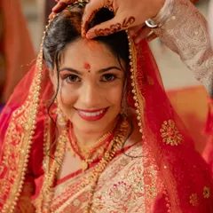 A candid moment from the main wedding ceremony. The bride is wearing a traditional red wedding saree, and her makeup is designed to be flawless and long-lasting through all the rituals.
