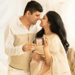A tender moment between a couple, sharing their joy as they look at their baby's first sonogram. The mother-to-be is dressed in a beautiful cream saree, captured in a soft, light-filled boho setting, making for a warm and intimate pregnancy portrait.