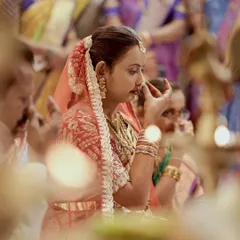 A quiet, reflective moment of a bride during her Hindu wedding ceremony, framed by the warm glow of ceremonial lamps.