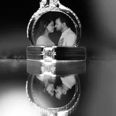 An artistic shot of the wedding rings, with the couple's reflection captured within. We believe in creative product photography that turns details like jewelry into a piece of the narrative.