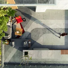 An aerial view of a rooftop terrace where curved floor patterns define zones for movement and pause. The space is outfitted with weatherproof seating and lush planters, making it a functional and visually striking urban garden.