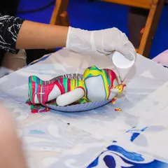 A guest gets creative with fluid art, pouring a rainbow of colors over a bear-shaped figurine to create a unique pattern.