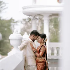 A quiet moment of togetherness captured against a classic white colonnade. We focus on capturing the gentle connection between two souls, preserving the authentic feeling of your wedding day in our South Indian wedding photography.