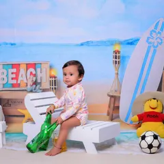 Our 'Beach Baby' theme brings the shore to the studio. I use a beach-themed backdrop, a miniature deck chair, a surfboard, and other fun props to create a sunny and playful setting for your child.