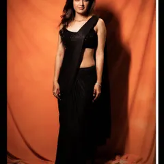 Actress Ashika Ranganath looks stunning in this sleek black saree gown. It's a pre-stitched drape that offers a perfect silhouette every time, paired with a simple sequined blouse for a chic and modern party look.