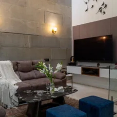 The complete view of the 'Casa Vitals' living area, showing the interplay of the stone wall, the TV unit, and the staircase, creating a cohesive modern look.