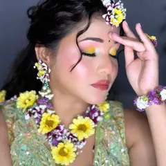 A close-up of the Haldi makeup, featuring a pop of yellow eyeshadow and rosy cheeks, perfectly complementing the floral jewelry.