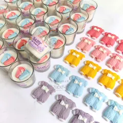 A vibrant collection of baby onesie shaped soy wax sachets and baby feet votive candles, showing the variety of colors and designs available for baby-related events.